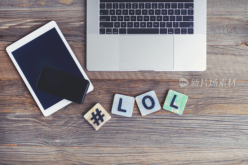 LOL是Laugh out loud的缩写。笔记本电脑，数字平板电脑和手机，标签和旁边的字母LOL。